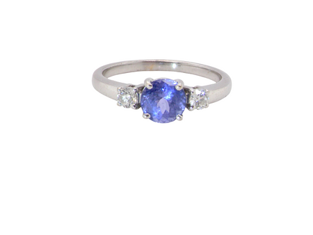 An 18 carat white gold three stone ring. Centre stone a round tanzanite 6mm diameter.
Each side a brilliant cut white diamond