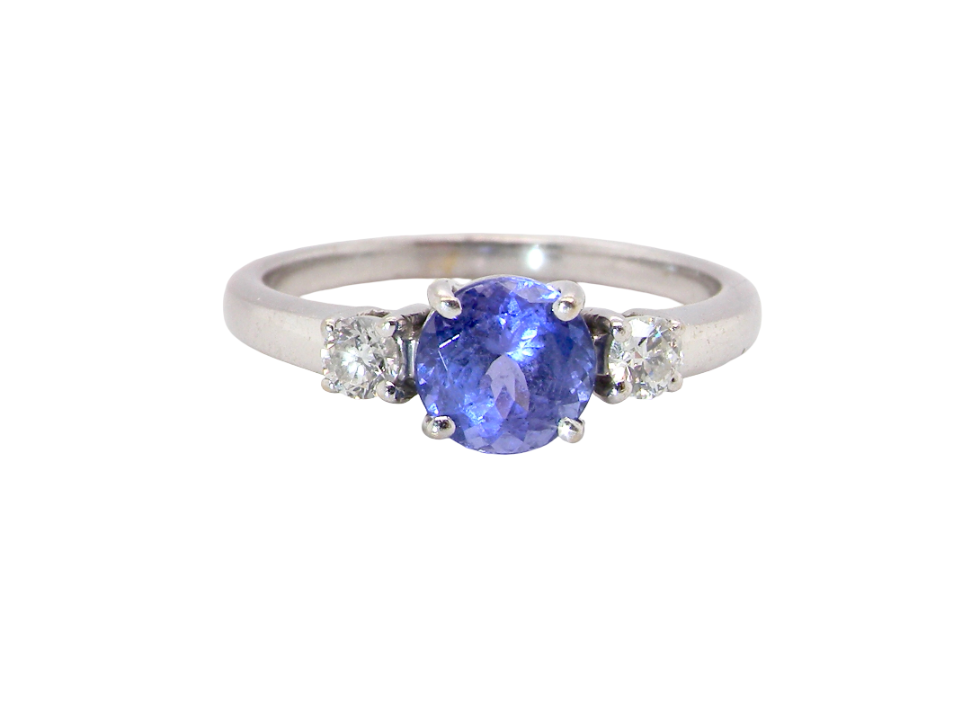 An 18 carat white gold three stone ring. Centre stone a round tanzanite 6mm diameter.
Each side a white diamond