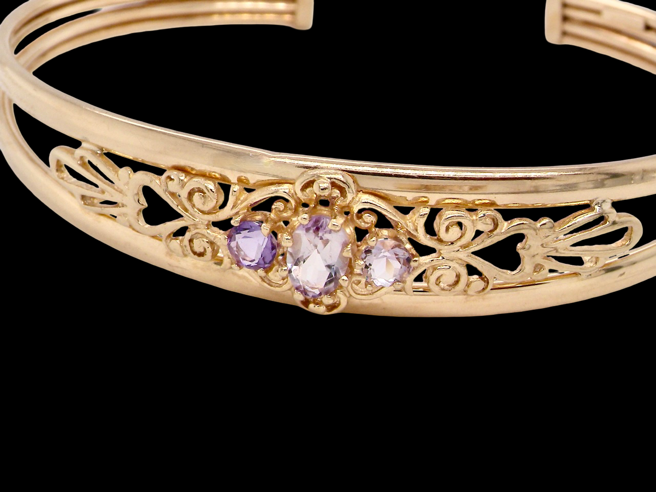 Gold bracelet with purple gemstones on a black background