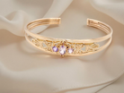 Gold bracelet with decorative elements and gemstones on a soft beige fabric background