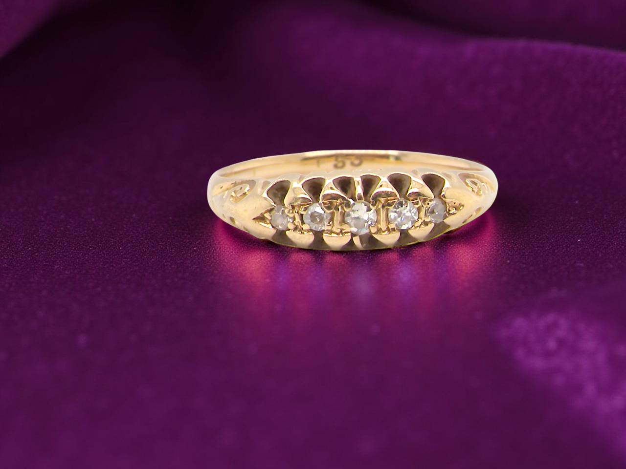 Gold ring with diamonds on a purple fabric background