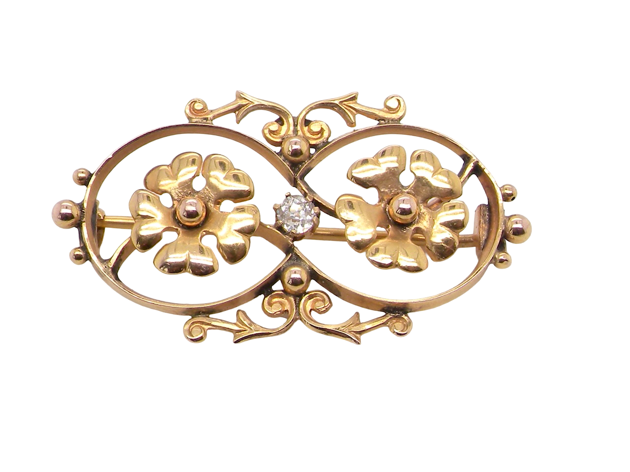 Gold brooch with floral designs and a central gemstone on a white background