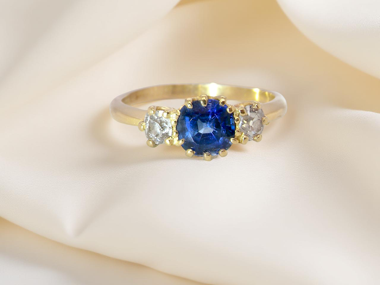 An early 20th-century trilogy ring set with a mid to dark cornflower blue sapphire, 