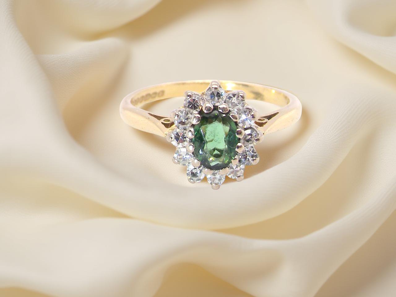 An elegant 18 carat gold cluster ring featuring a beautifully proportioned green tourmaline 