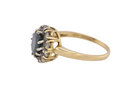 A An elegant 18 carat gold cluster ring featuring a striking inky dark blue sapphire at its centre. 