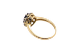 side An elegant 18 carat gold cluster ring featuring a striking inky dark blue sapphire at its centre. 