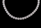 A diamond tennis necklace with cushion-cut diamonds set in a silver-toned metal, shown against a solid black background.