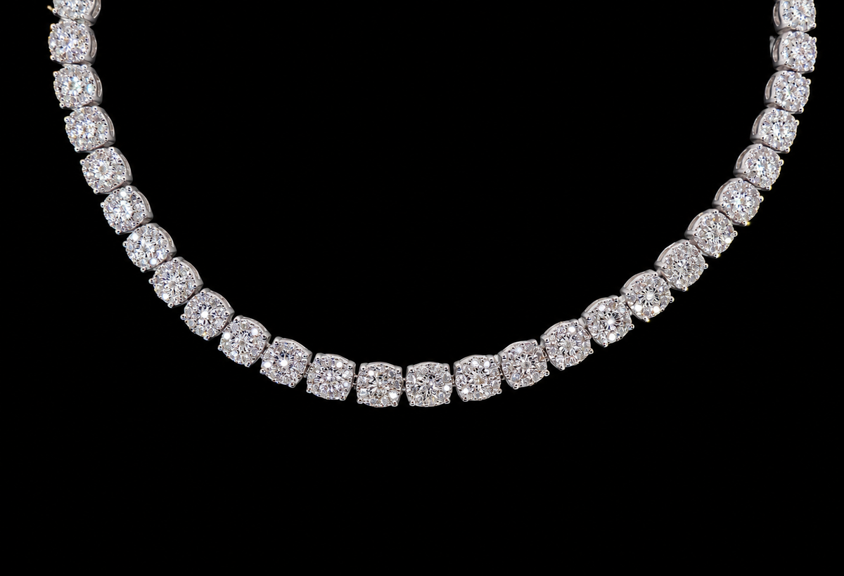 A diamond tennis necklace with cushion-cut diamonds set in a silver-toned metal, shown against a solid black background.