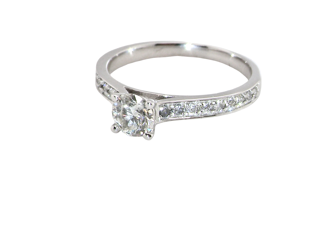 A diamond engagement ring with a round-cut center stone and a pavé-set diamond band, shown on a plain white background.
