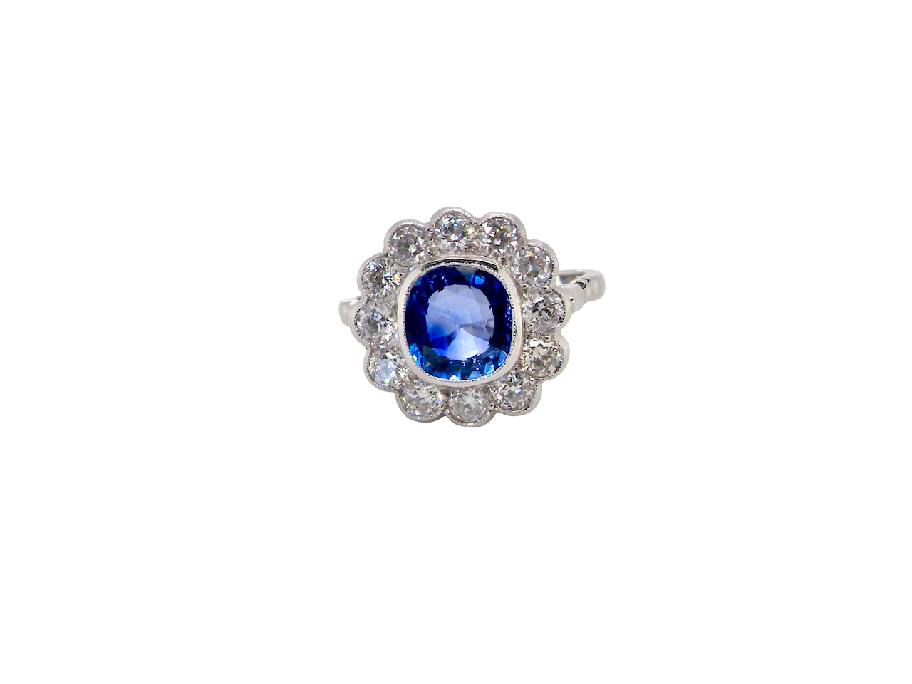 An elegant and timeless cluster ring, centrally set with a beautiful mid to deep blue cushion-cut sapphire, measuring approximately 8 x 8mm (estimated 2.00 carats). 