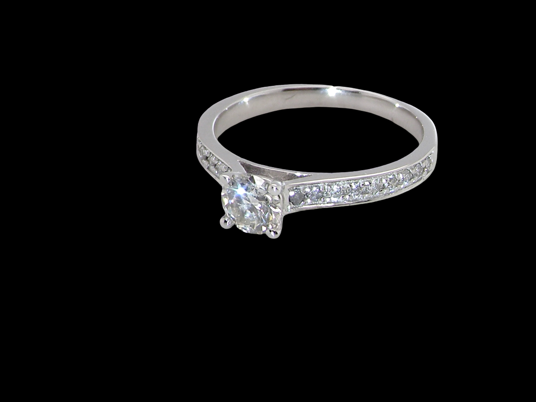 A diamond engagement ring with a round center stone and pavé-set diamonds on the band, shown against a solid black background.