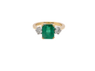 An exceptional three-stone ring featuring a vibrant step-cut emerald to the centre, measuring 8.6 x 7.0mm and weighing approximately 2.10 carats. The emerald displays a beautiful grass-green colour and is secured in a classic four-claw setting.
