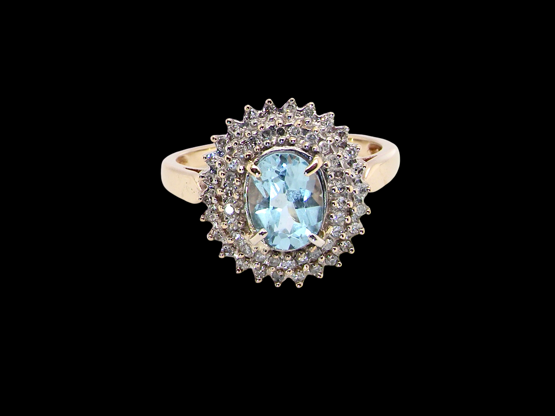 An impressive cluster ring that features to the centre an oval cut blue topaz gemstone, 8x6mm sky blue colour.

Complimented by a double halo of diamonds