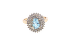 An impressive cluster ring that features to the centre an oval cut blue topaz gemstone, 8x6mm sky blue colour.

Complimented by an outer double halo of diamonds