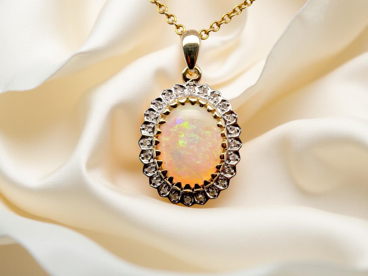Opal pendant with gold frame and chain on white fabric