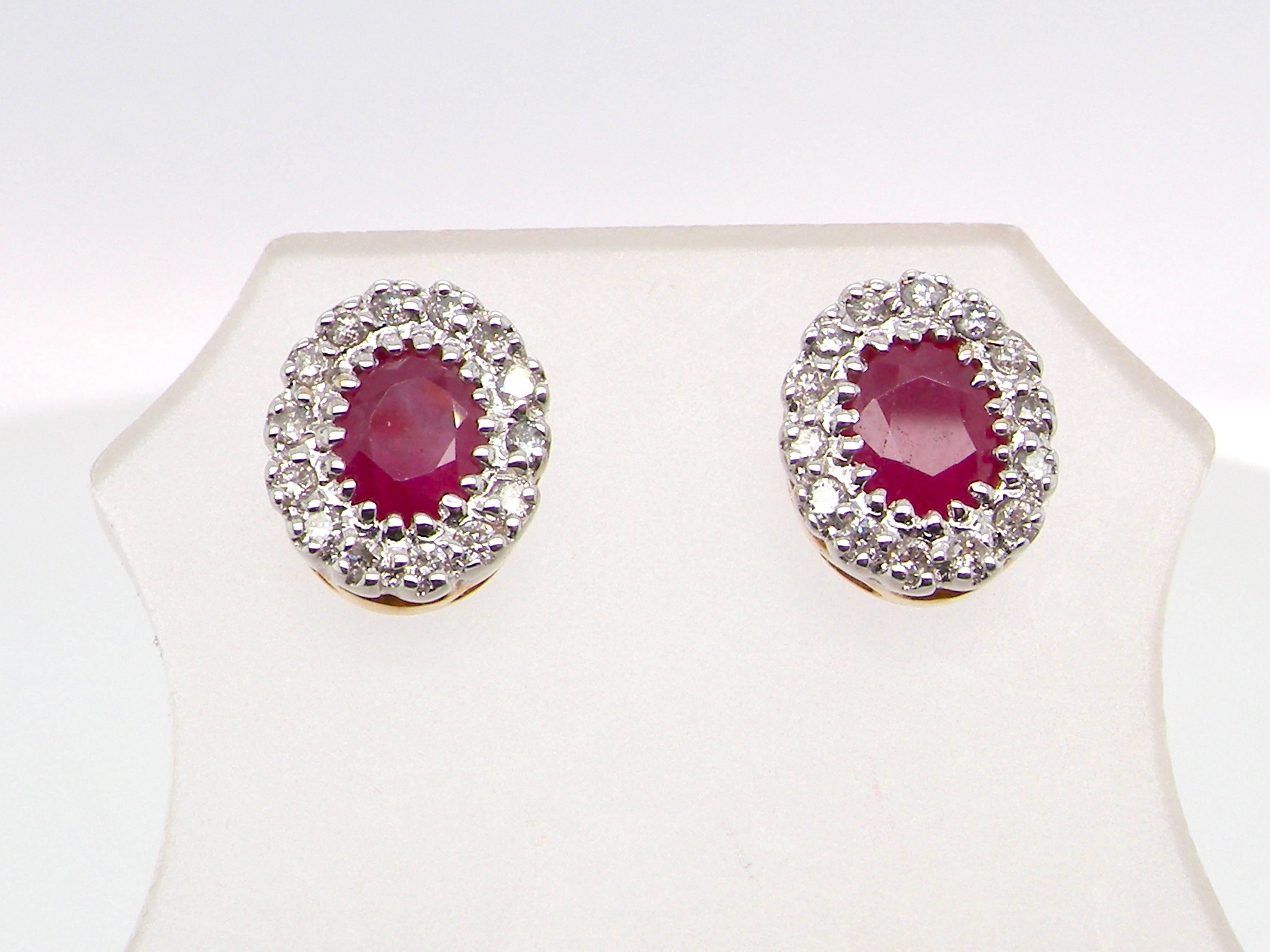 Pair of earrings with red gemstones and diamond-like accents on a white background