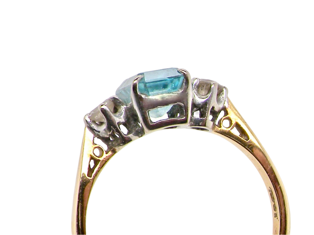 A three stone blue zircon and diamond ring under view