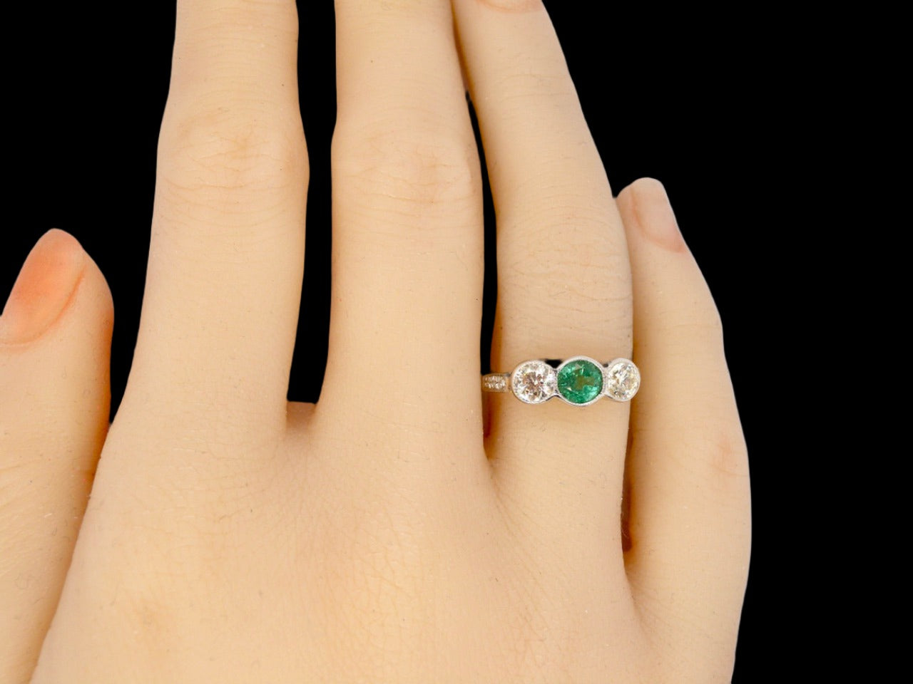 An Emerald and Diamond three stone ring finger view