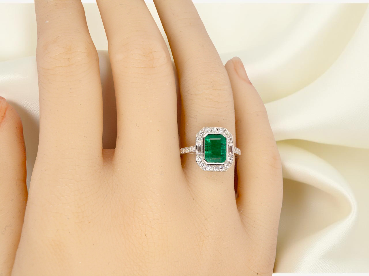 Emerald ring on a hand with a soft white background