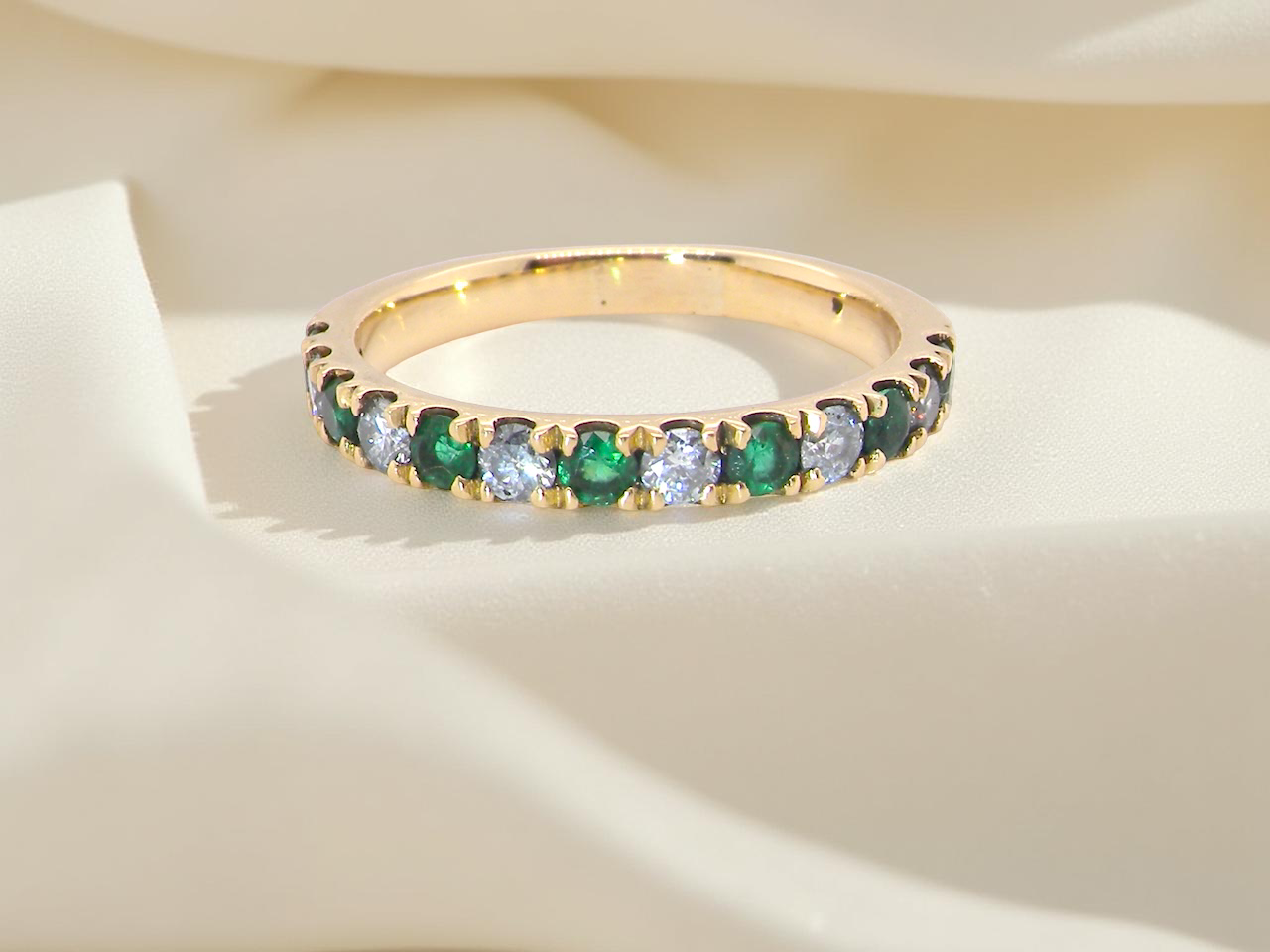 gold eternity ring with green and clear gemstones