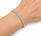  tennis bracelet with round-cut clear stones, shown worn on a person's wrist against a plain white background.