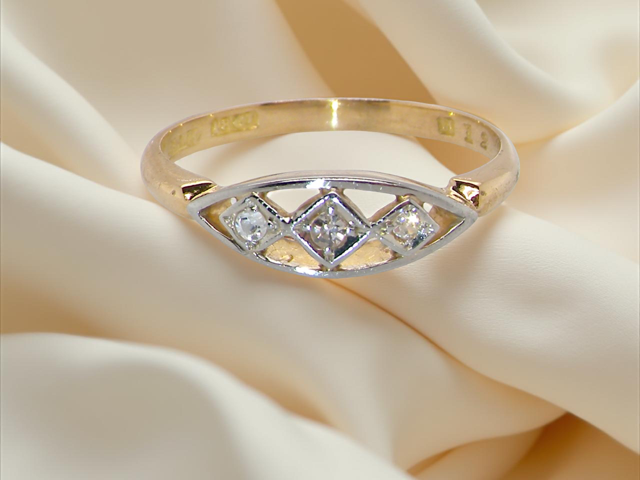 Gold ring with diamonds on a soft beige fabric background