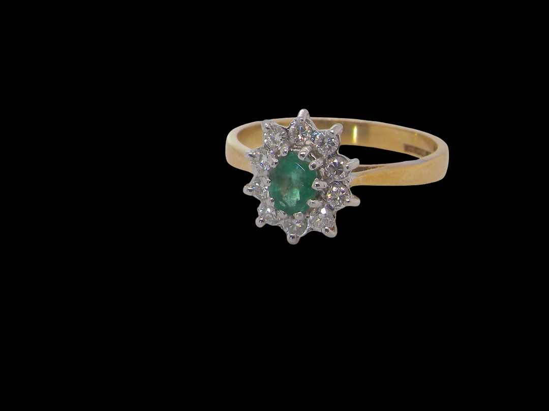  Features to the centre an oval shaped emerald, 5.5x4.5mm (est 0.35 carats) deep green colour.&nbsp;