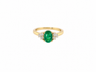 A yellow gold ring featuring an oval-cut green emerald center stone, flanked by small clusters of clear stones on either side, set against a plain white background.