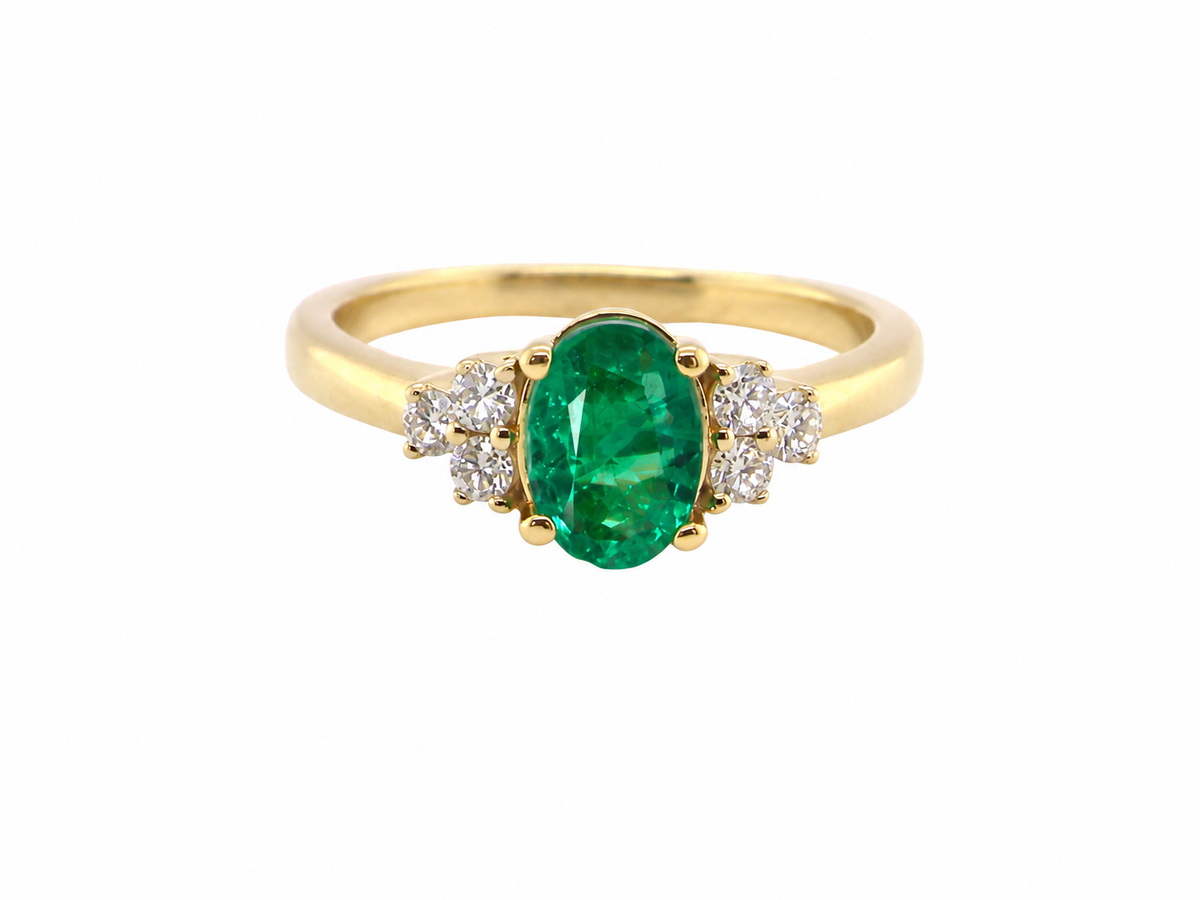 Featuring a lovely deep velvety green emerald centre stone, this 18 carat gold ring is enhanced by six brilliant cut white diamonds.
