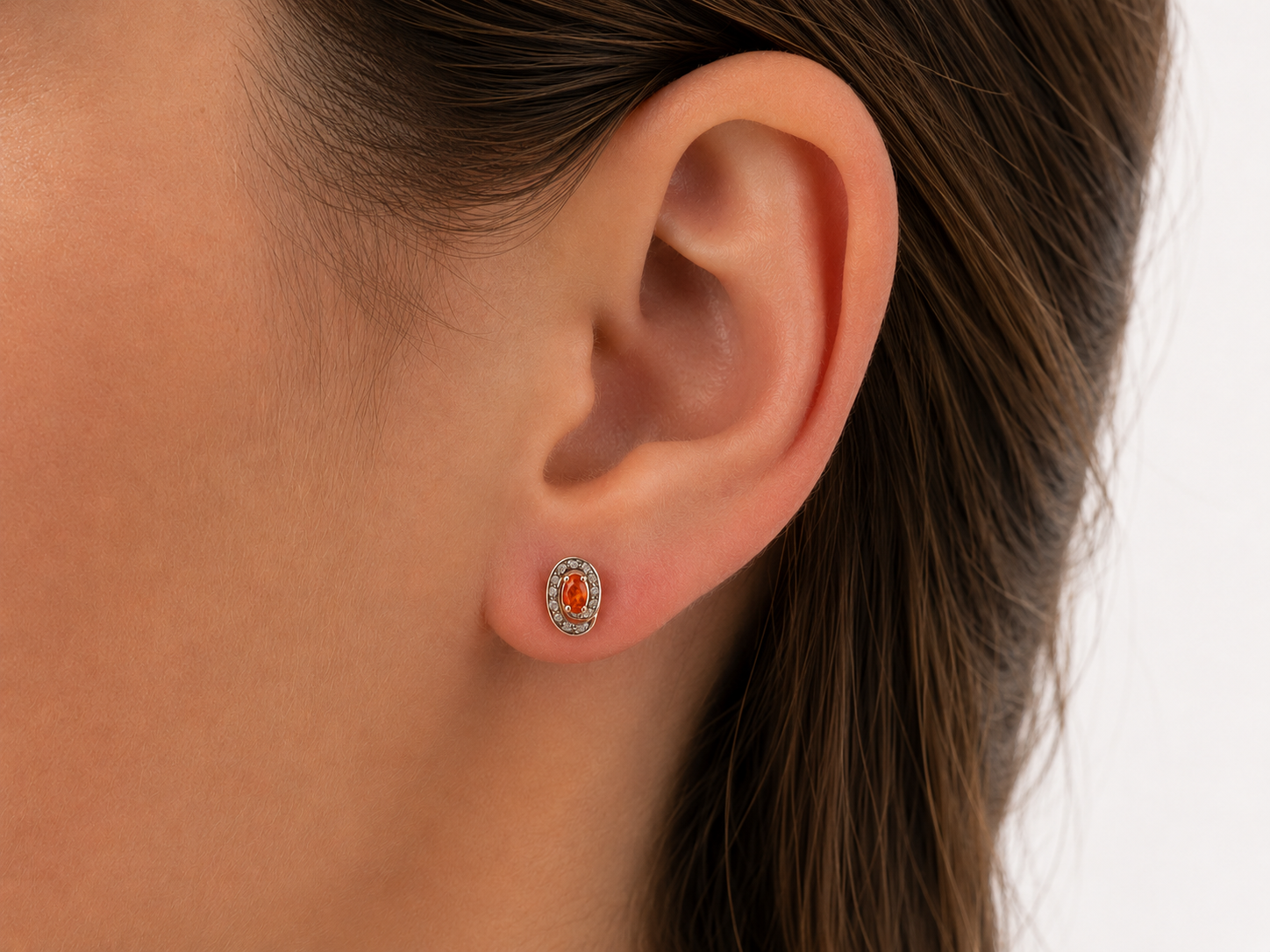 Pair of earrings with fire opals on a ear