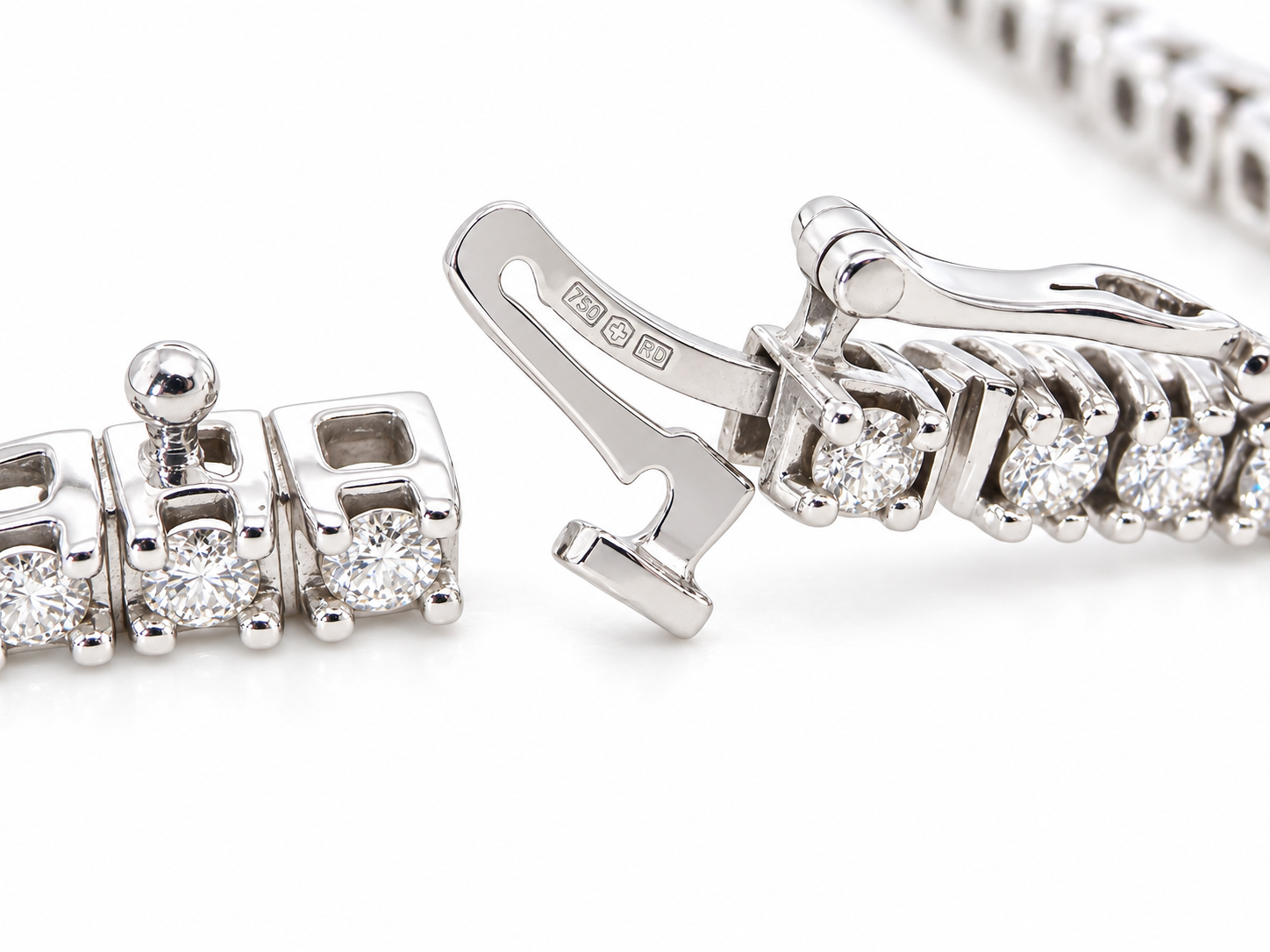 Close-up of a silver-toned tennis bracelet showing the clasp mechanism and a section of the linked chain with clear gemstones on a white background.