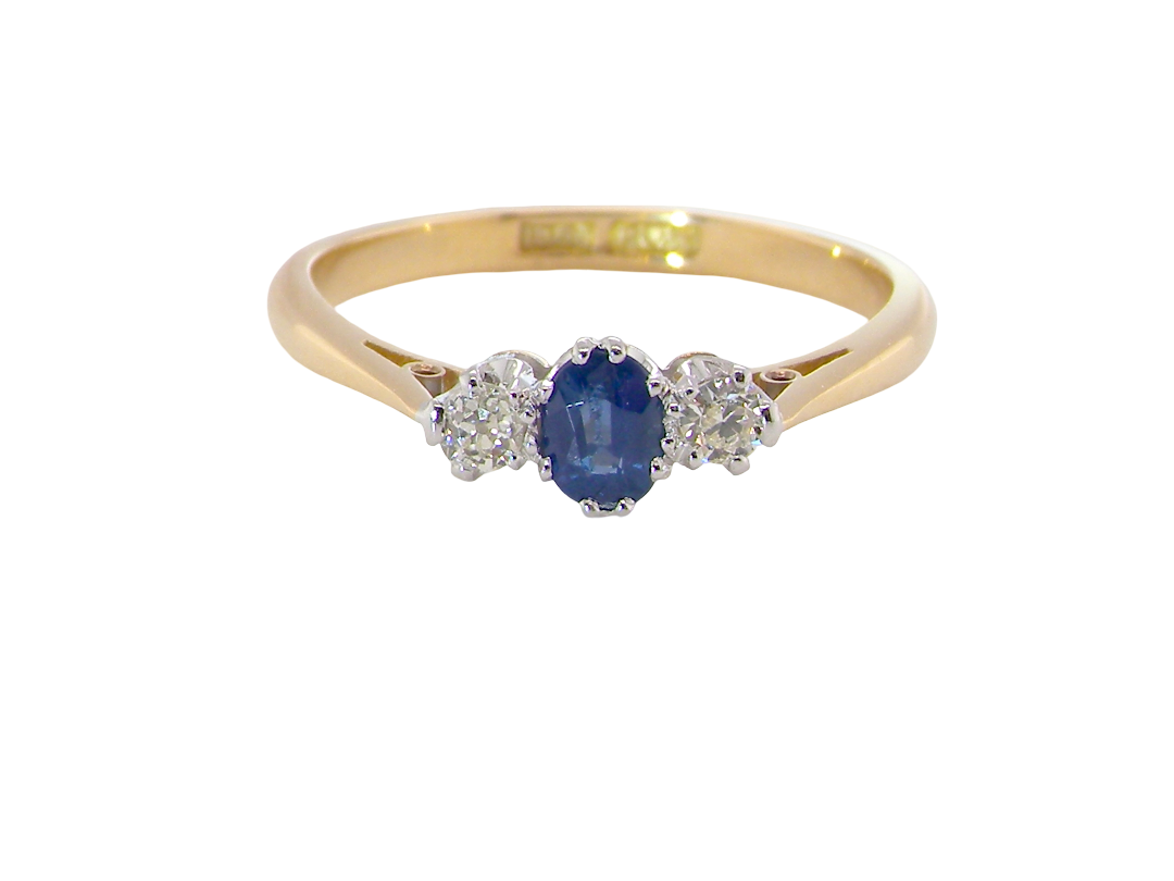 The classic trilogy ring, this features to the centre a round mid to dark blue sapphire and each side a brilliant cut white diamond