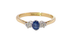 The classic trilogy ring, this features to the centre a round mid to dark blue sapphire and each side a brilliant cut white diamond