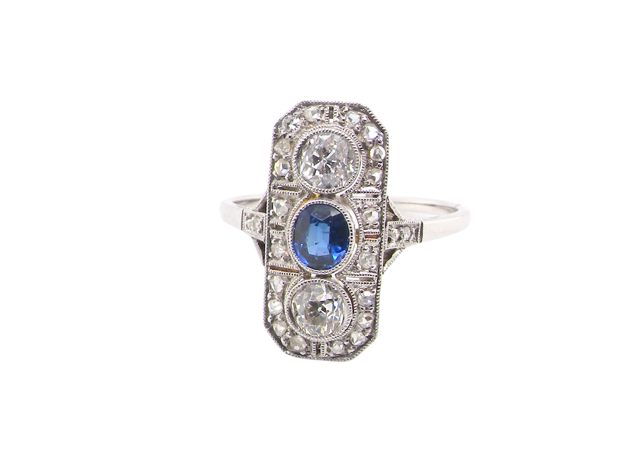 The plaque design has at its centre a mid to dark blue sapphire, 5x4mm (est 0.40 carats) mille grain set. Above and below to Old European Cut white diamonds. Each one estimated at 0.40 carats (4.8mm) 
