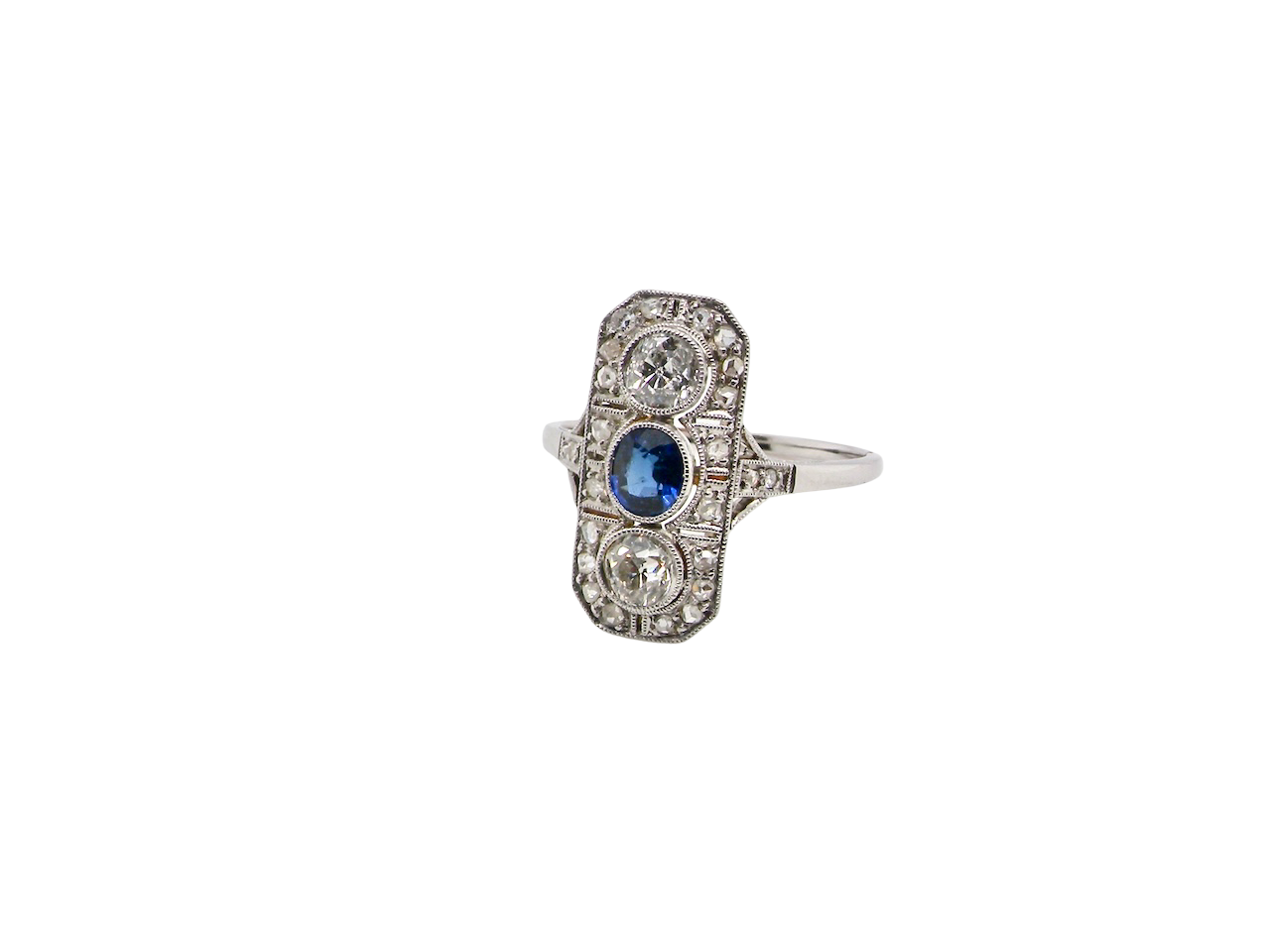 The plaque design has at its centre a mid to dark blue sapphire, 5x4mm (est 0.40 carats) mille grain set. Above and below to Old European Cut white diamonds. Each one estimated at 0.40 carats (4.8mm) Colour H-j, clarity Si.
