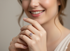 Woman wearing a ring with a diamond and ruby on a neutral background