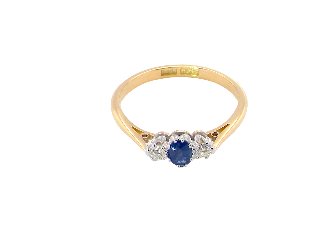 above view The classic trilogy ring, this features to the centre a round mid to dark blue sapphire and each side a brilliant cut white diamond