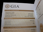 A close-up of an GIA Natural Diamond Dossier document page showing diamond grading details, including carat weight, color grade, clarity grade, and polishing quality.