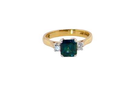 elegant 18 carat yellow gold trilogy ring featuring a striking natural sapphire at its centre