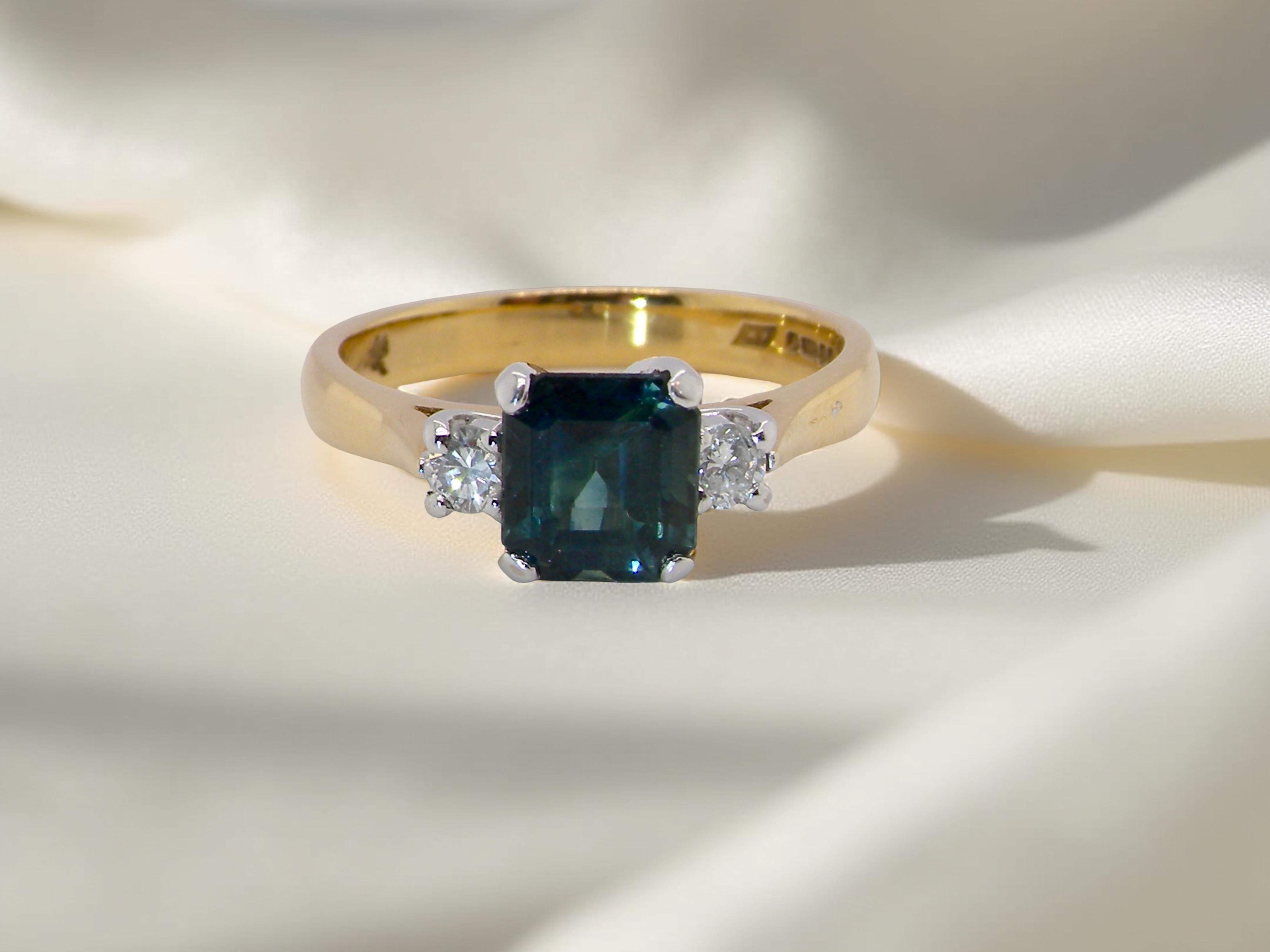 elegant 18 carat yellow gold trilogy ring featuring a striking sapphire at its centre