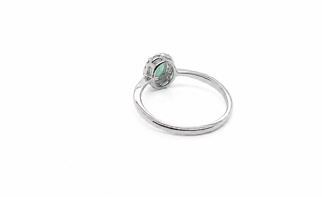 white gold ring with a green gemstone on a white background reverse image 