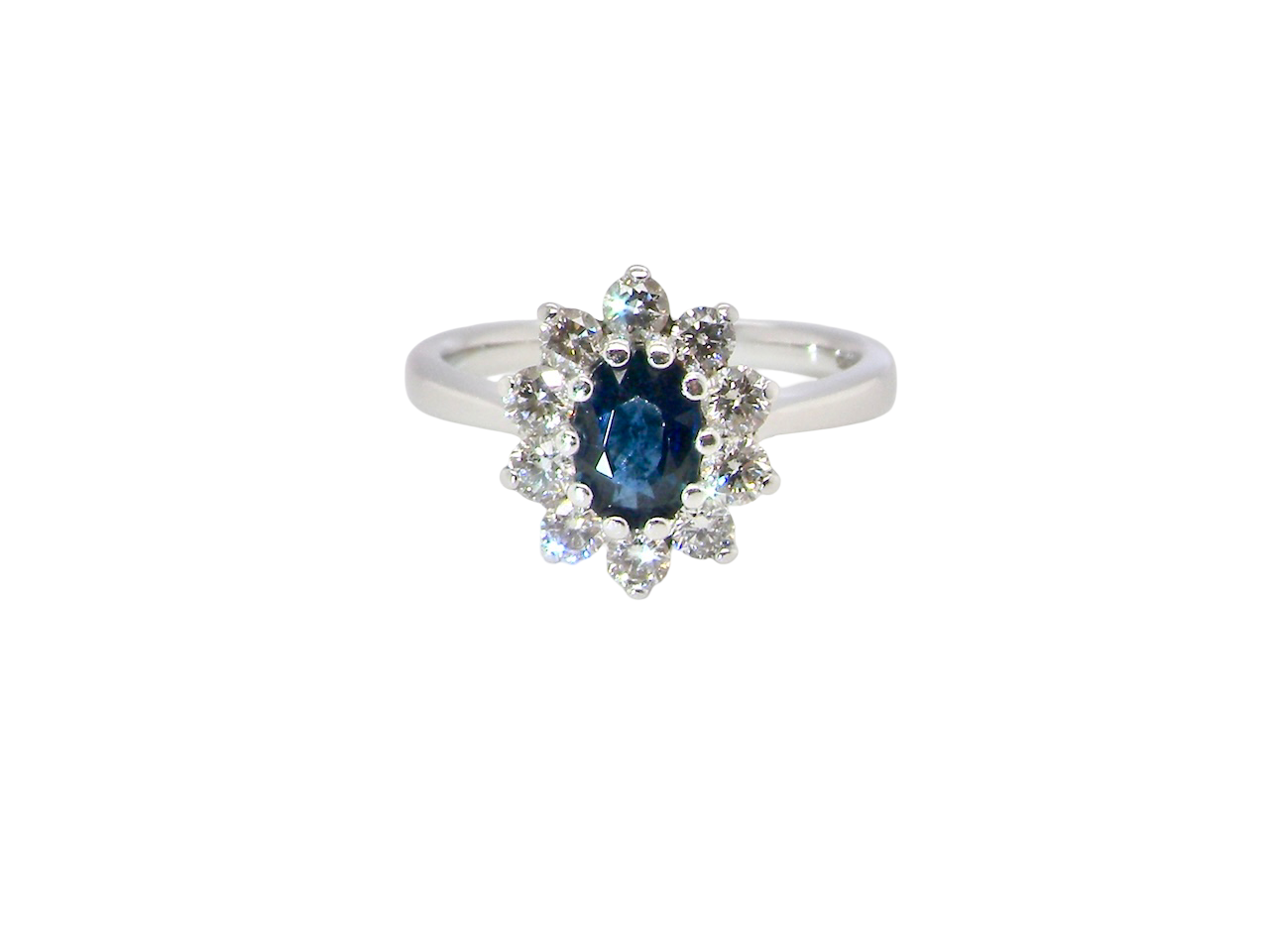  fine 18 carat white gold cluster ring. Features an oval cut dark blue sapphire centre stone 