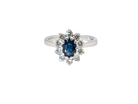 fine 18 carat white gold cluster ring. Features an oval cut dark blue sapphire centre stone 