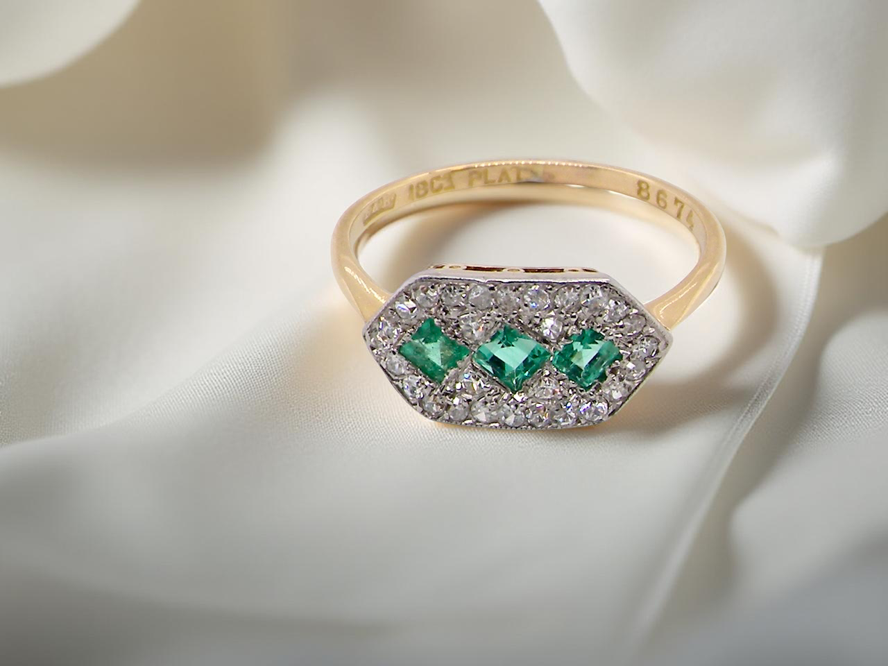  fine Edwardian era cluster ring, beautifully handcrafted with a trio of vibrant emeralds surrounded by a halo of antique  diamonds. 