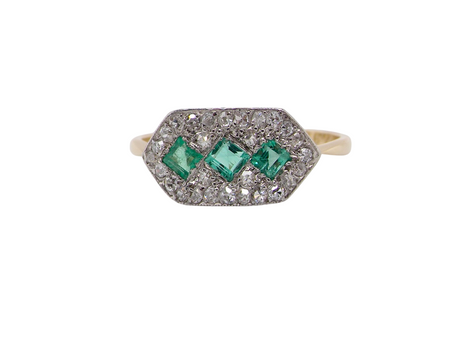  fine Edwardian era cluster ring, beautifully handcrafted with a trio of vibrant emeralds surrounded by a halo of old-cut diamonds. 