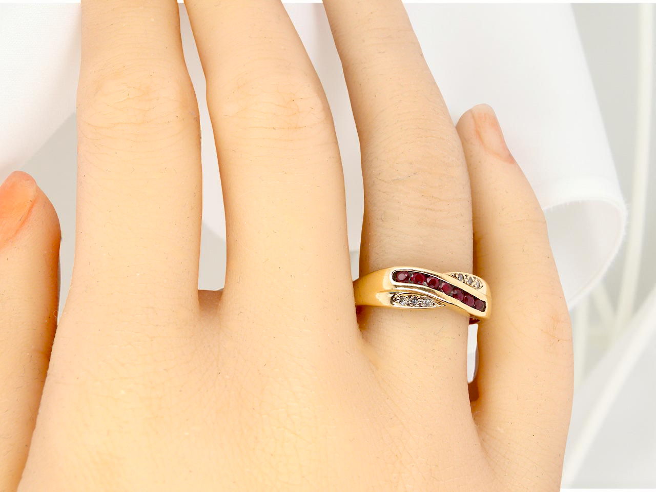 A 9 carat Gold Crossover Ring with Rubies and Diamonds on a Hand