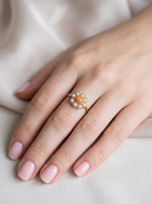 hand A 9 carat gold cluster ring. Centre stone an oval shaped coral stone 6x4mm.
