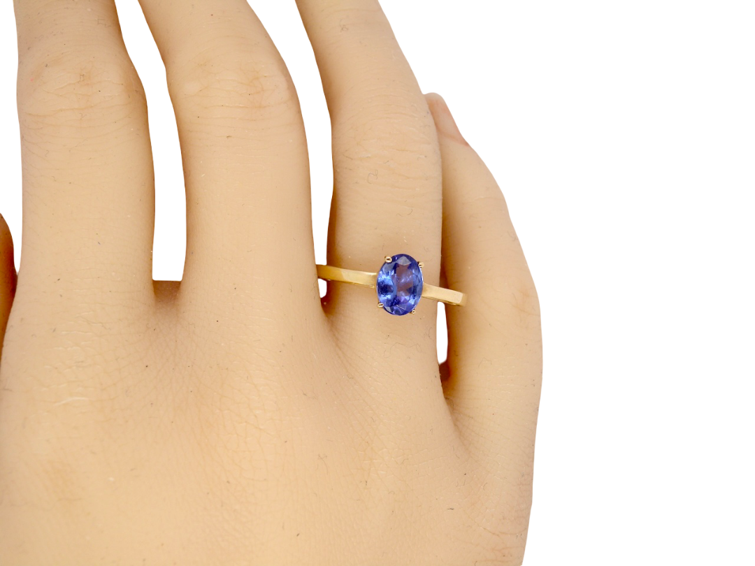 hand A 9 carat gold ring containing a single oval cut tanzanite gemstone. Measures 8x6mm, four claw setting.