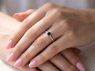 hand A 9 carat white gold solitaire ring. Features a round dark blue sapphire, 4.6mm diameter (est 0.38 carats) Rim set.
