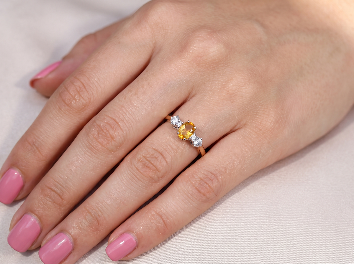 hand A beautiful 18 carat yellow gold trilogy ring, combining the warm golden tones of a yellow sapphire with&nbsp; white diamonds.